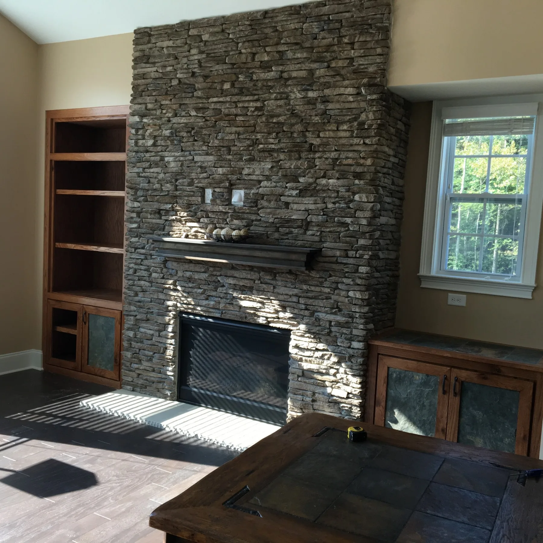 Oak built-in cabinets set into a ledge stone fireplace wall