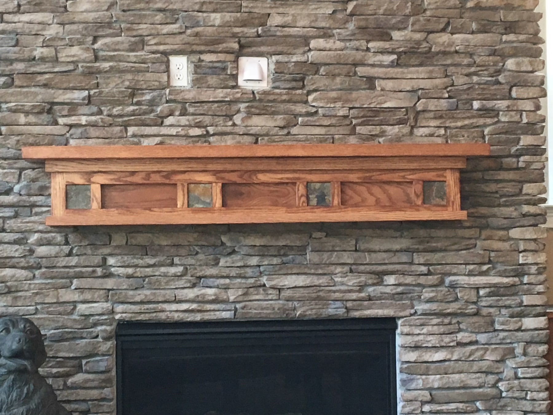 Oak mantel with slate inserts on a ledge stone fireplace