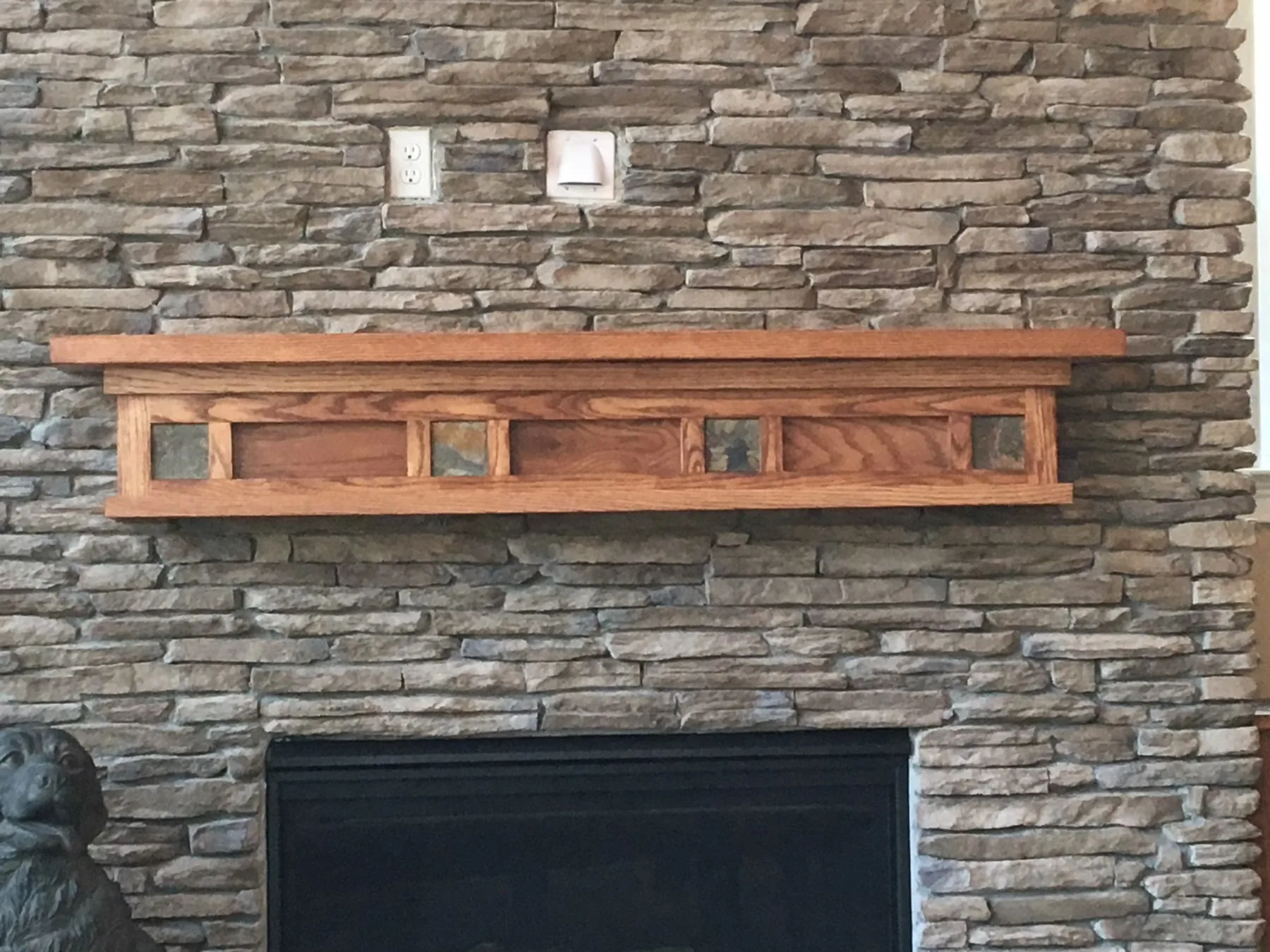 Oak mantel with slate inserts on a ledge stone fireplace